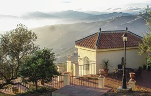A building with a tiled roof, a balcony with a railing, and a view of distant mountains. - Amazing home in Algarrobo (Algarrobo)