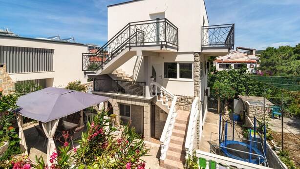 Et moderne hus med to etager, en balkon, en trappe og et poolområde.