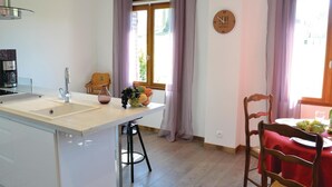 A kitchen with a central island, a coffee machine, a sink, and a dining area with a table set for two. - 3 bedroom cozy home in Frise (Frise)