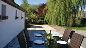 An outdoor dining area with a table set for two, surrounded by wicker chairs, and a bottle of wine on the table. - 3 bedroom cozy home in Frise (Frise)