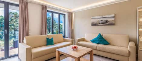 A modern living room with two beige sofas, a wooden coffee table, and a painting on the wall.