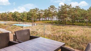 Eine Terrasse mit Korbmöbeln, einem Pool und Blick auf Bäume.