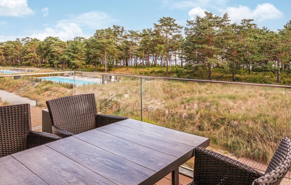 A terrace with wicker furniture, a pool, and a view of trees.