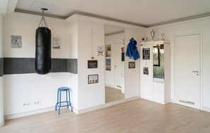 A room with a punching bag, a blue stool, a mirror, and a door with a mirror.