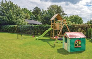 A wooden play structure with a slide and climbing area, a small green playhouse, and a soccer goal in a grassy yard. - Nice home in Hadsund with WiFi (Hadsund)