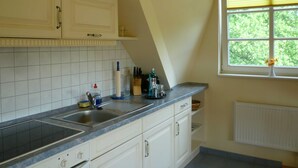 Una cocina con ventana, armarios blancos, un lavamanos y una encimera.