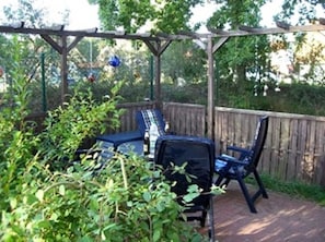 A covered patio with a wooden pergola, a table, and two chairs. - Apartment Lilly - Apartment Glowe (Glowe)