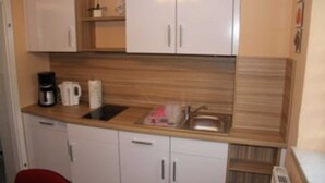 A compact kitchen with white cabinets, a wooden countertop, a coffee maker, and a sink.
