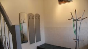 A room with a bed, a wooden bench, a coat rack, and a wall-mounted mirror.
