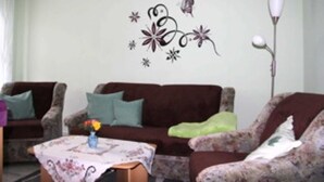 A living room with patterned sofas, a coffee table with a vase, and a wall decoration.