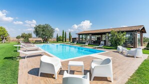 Ein Schwimmbecken mit Liegestühlen und einer überdachten Terrasse.