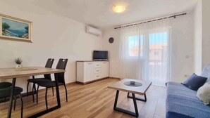 Un espacio habitable compacto con comedor, sofá, televisor y un cuadro en la pared.