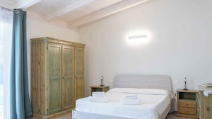 Une chambre à coucher comprenant un lit, des tables de chevet, une armoire et un luminaire.