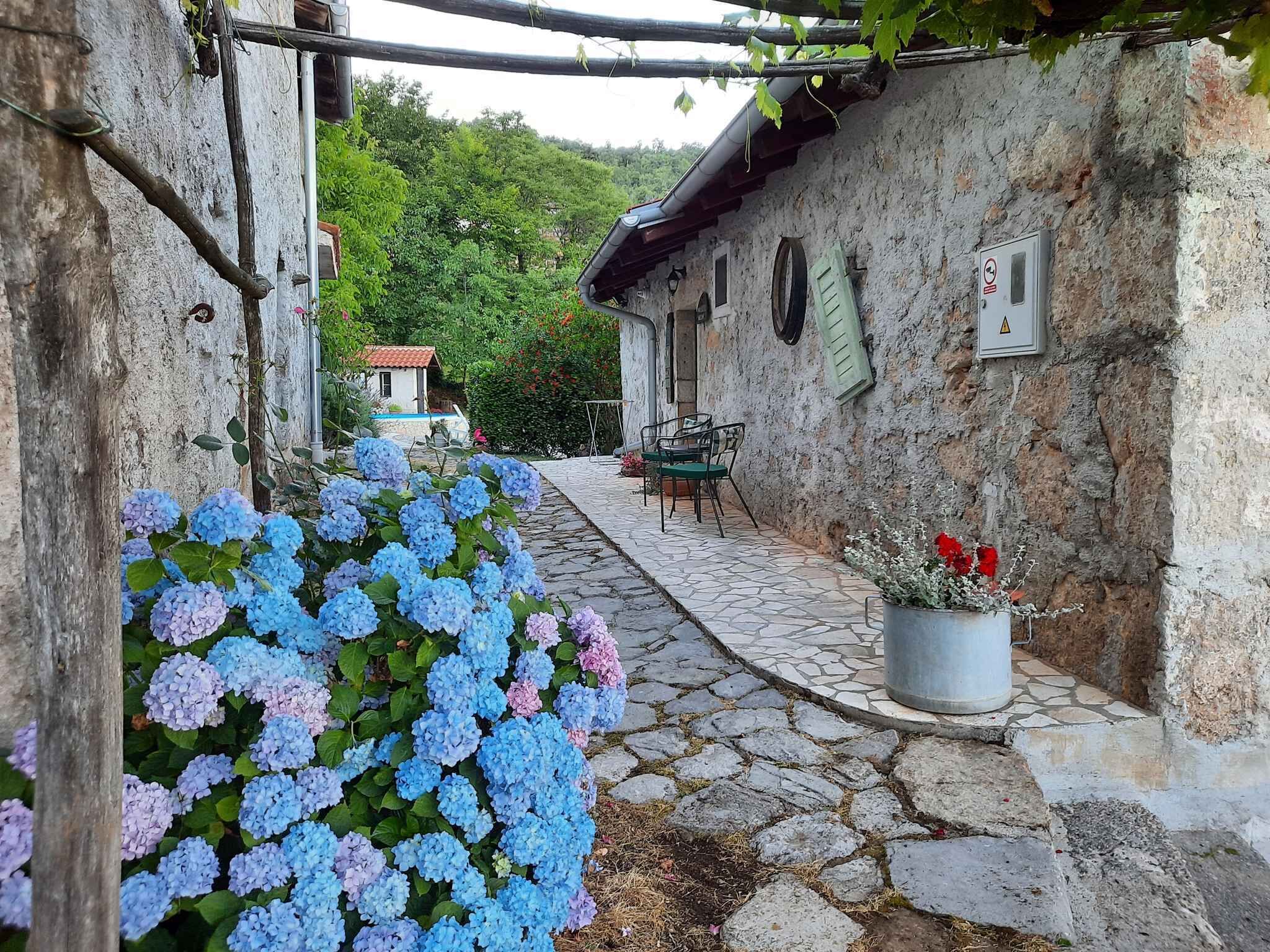 Un étroit sentier de pierres mène à un bâtiment rustique doté d’un petit patio.