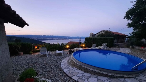 A swimming pool with lounge chairs and a view of a distant cityscape. - Holiday home with sea view and pool (Dobreć)