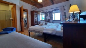 A bedroom with two beds, wooden ceiling beams, stone walls, and a window with curtains. - Holiday home with sea view and pool (Dobreć)