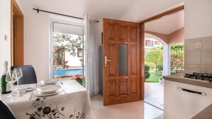 Un comedor con una mesa dispuesta para dos personas, vista a una piscina y una puerta de madera que da a un patio exterior.