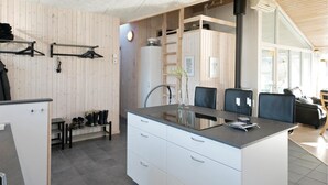 Moderni keittiö, jossa on keskeinen saareke, valkoiset kaapit ja puinen seinä.
