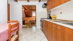 Una cocina compacta con armarios de madera, un lavamanos y una zona de comedor con mantel a cuadros.
