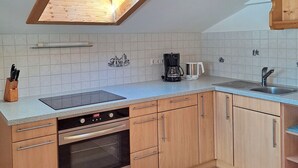 Una cocina con tragaluz, lavavajillas, horno y cafetera.