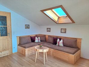 Une pièce chaleureuse avec un banc en bois, une petite table et une lucarne.