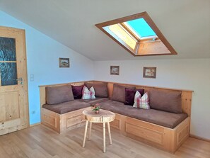 A cozy room with a wooden bench, a small table, and a skylight. - Blauberg vacation apartment - Nagel vacation apartments, Kreuth-Enterbach (Kreuth)