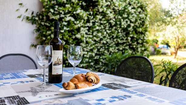Una mesa con una botella de vino, dos copas y un plato de cruasanes.