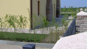 A building with a yellow facade, stone chimneys, and a small garden area with young trees. - Studio with air conditioning and pool (Ariano nel Polesine)