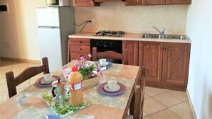 A kitchen with wooden cabinets, a gas stove, a microwave, and a sink. - Studio with air conditioning and pool (Ariano nel Polesine)