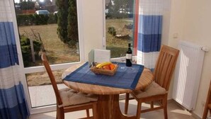 A dining area with a table set for two, a bottle of wine, and a fruit basket. - Tern (House 167) - FH 167 (Mönkebude)