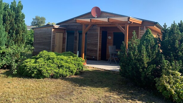 A wooden cabin with a covered porch, a satellite dish, and a small patio area. - Tern (House 167) - FH 167 (Mönkebude)