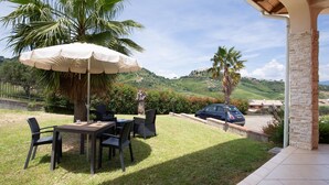 An outdoor patio with a table and chairs, a large umbrella, and a view of a hilly landscape. - Beautiful home in Rende -CS- with WiFi (Rende -CS-)