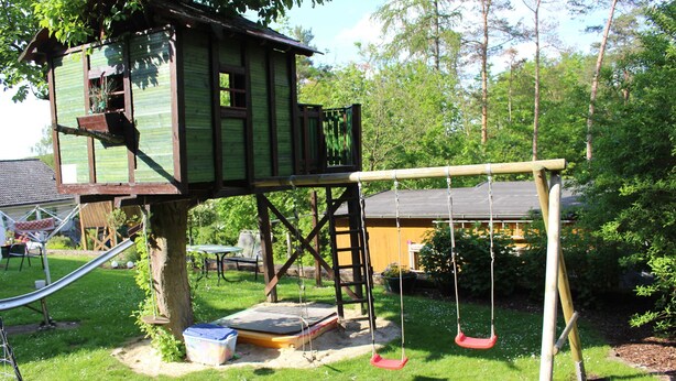 A treehouse with a swing set, a slide, and a trampoline. - Apartment - Holiday apartments Haus Waldesruh (Edertal)