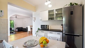 Een moderne keuken met een roestvrijstalen koelkast, een magnetron en een eethoek met een tafel gedekt voor twee personen.