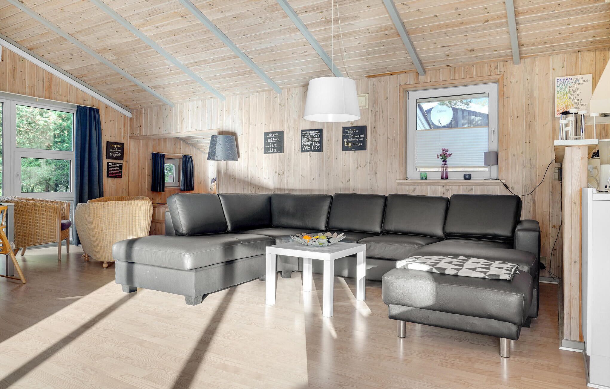 Un salon moderne avec un canapé d’angle, une petite table blanche et une fenêtre avec des rideaux.