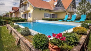 A two-story house with a swimming pool, blue lounge chairs, and a well-maintained garden. - Studio 50 m from the shore of Lake Balaton, with pool (Balatonmáriafürdő)