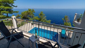 Ein Balkon mit Pool, der auf ein Gewässer und entfernte Landblicke blickt.