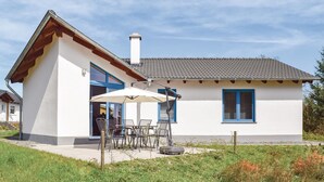 A single-story house with a white exterior and blue shutters, a patio with outdoor furniture, and a clear sky. - Amazing home in Gerolstein with kitchen (Gerolstein)