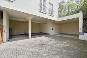 A building with a covered entrance, a staircase, and a paved courtyard.