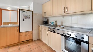 Een keuken met houten kastjes, een roestvrijstalen koelkast, een vaatwasser en een oven.