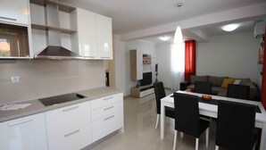 Una cucina moderna con mobili bianchi, una cappa aspirante in acciaio inossidabile e un'area pranzo con tavolo bianco e sedie nere.