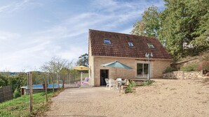 Ein zweistöckiges Steinhaus mit einem eingezäunten Hinterhof, einem Pool und Gartenmöbeln.