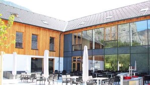 A modern building with a wooden facade and large glass windows reflecting the surrounding landscape.