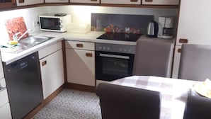 Una cucina compatta con lavastoviglie, microonde, fornello e un tavolo con sedie.