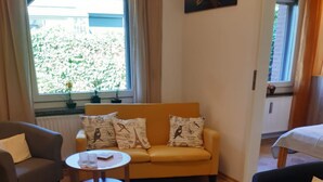 Un soggiorno con un divano giallo, due poltrone, un tavolino rotondo e un tappeto decorato.