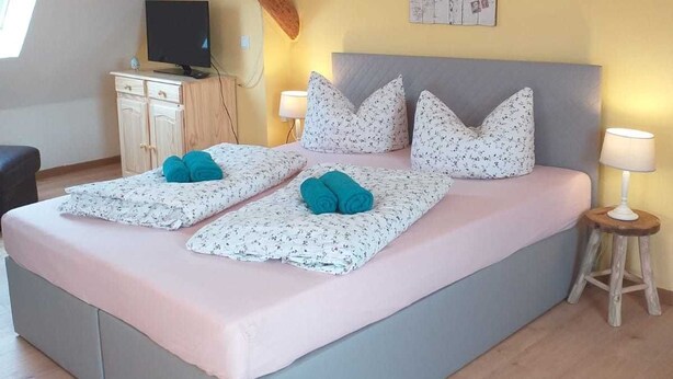 Une chambre à coucher avec un lit, une télévision, un bureau et un tableau accroché au mur.