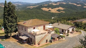 A stone building with a tiled roof, a staircase, and outdoor seating. - Beautiful apartment in Pomarance (Pomarance)