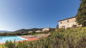 A pool area with lounge chairs and a stone building with a tiled roof. - Beautiful apartment in Pomarance (Pomarance)