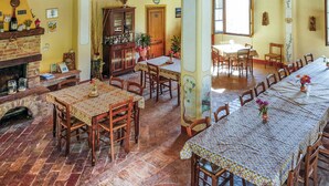 A traditional dining room with wooden tables and chairs, a brick fireplace, and a wooden cabinet. - Beautiful apartment in Pomarance (Pomarance)