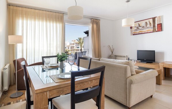 A modern living room with a dining table, sofa, and TV.